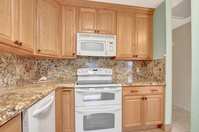 kitchen with light stone counters, light tile patterned floors, white appliances, and decorative backsplash