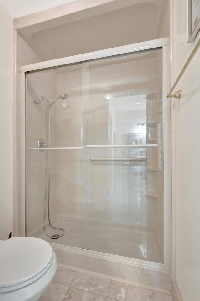 bathroom featuring toilet and an enclosed shower