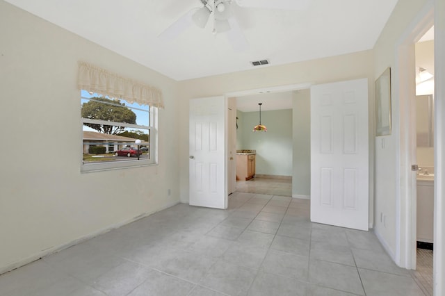 tiled empty room featuring ceiling fan