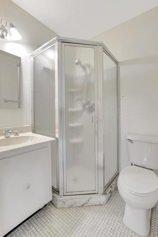 bathroom with tile patterned flooring, vanity, toilet, and walk in shower