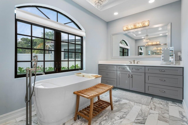 bathroom with recessed lighting, vanity, baseboards, a freestanding bath, and marble finish floor