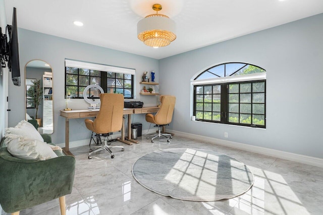 office space featuring arched walkways, marble finish floor, plenty of natural light, and baseboards