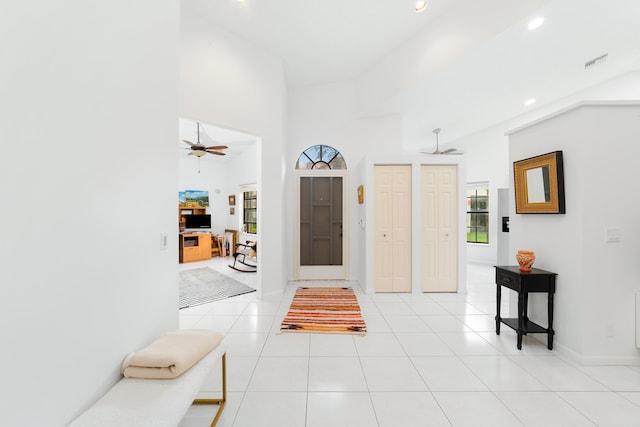 entryway featuring a towering ceiling, ceiling fan, and light tile patterned floors