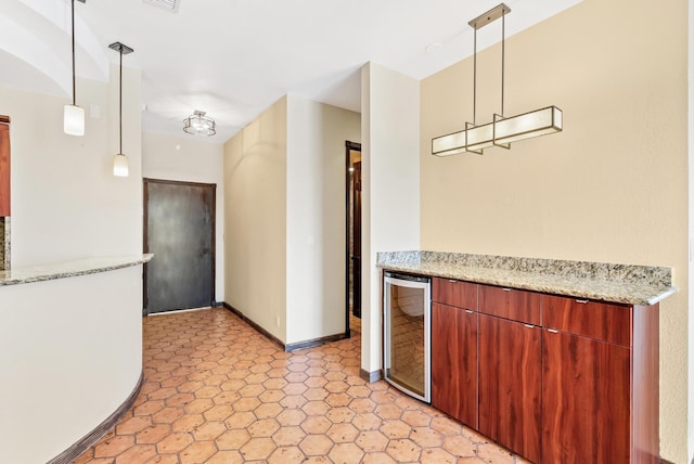 kitchen featuring beverage cooler, visible vents, baseboards, hanging light fixtures, and light stone countertops