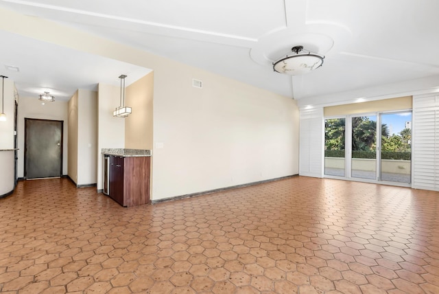 unfurnished living room featuring vaulted ceiling, visible vents, and baseboards