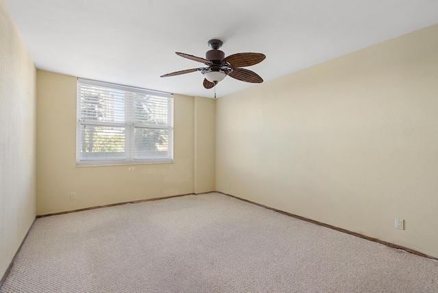 empty room featuring ceiling fan, baseboards, and light colored carpet