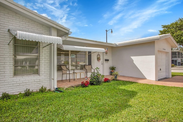 view of front facade with an attached garage, stucco siding, covered porch, and a front yard