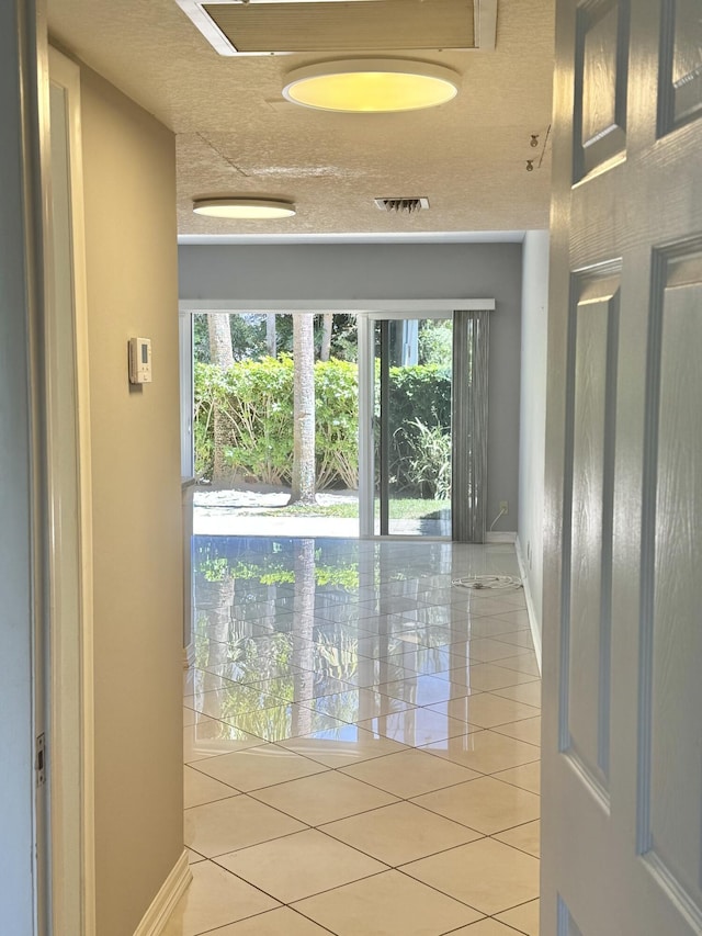 interior space featuring baseboards, light tile patterned flooring, and visible vents