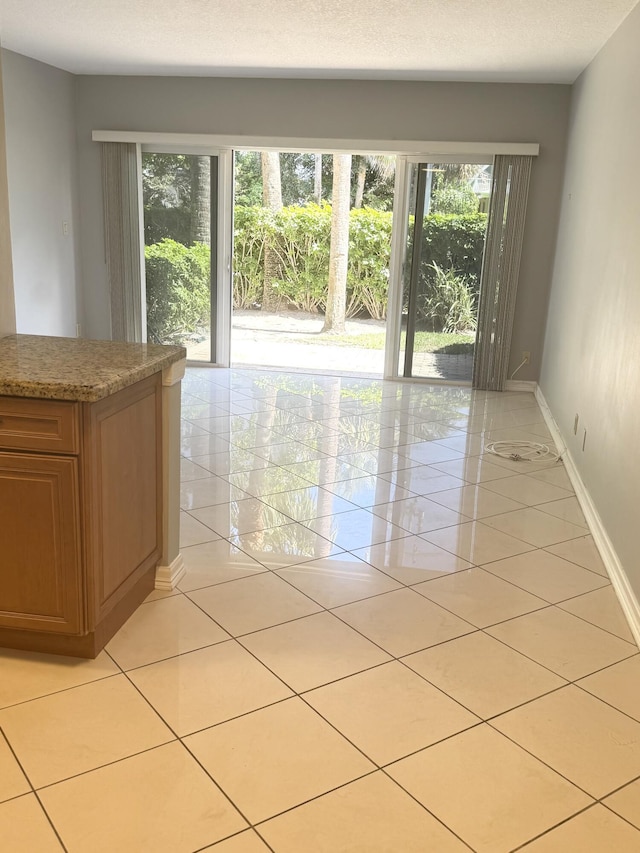 spare room with baseboards, light tile patterned flooring, and a wealth of natural light