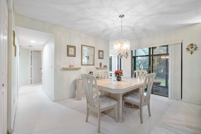 carpeted dining room featuring a chandelier and a textured ceiling