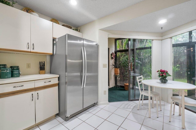 kitchen featuring white cabinetry, light tile patterned floors, stainless steel refrigerator, and a textured ceiling