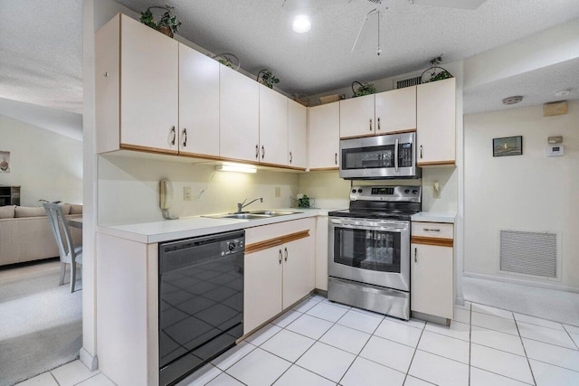 kitchen with light tile patterned flooring, sink, white cabinets, stainless steel appliances, and a textured ceiling