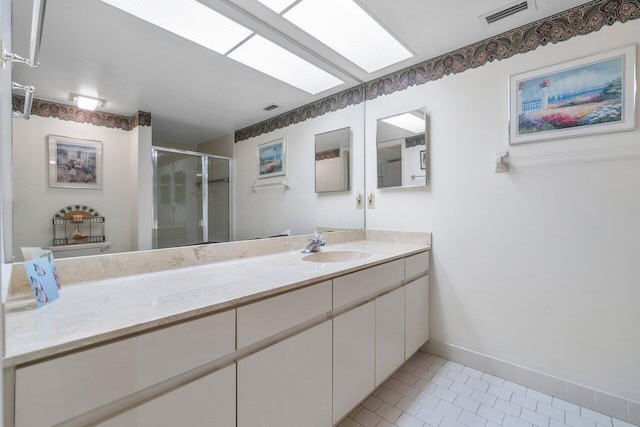 bathroom featuring tile patterned flooring, a skylight, vanity, a shower with shower door, and toilet