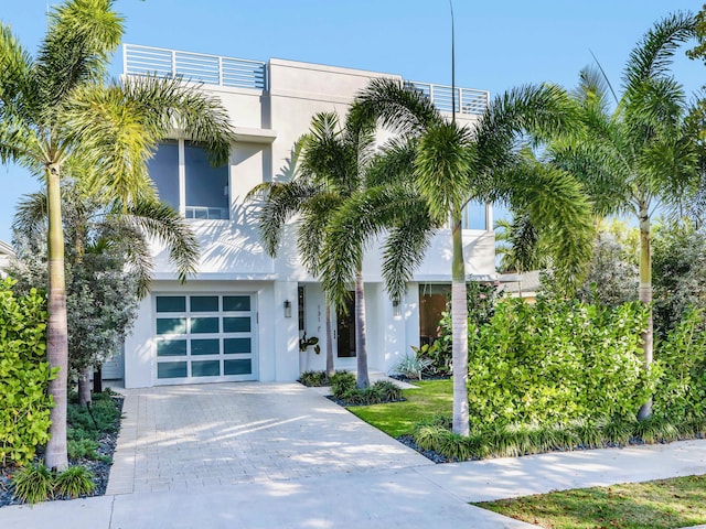 contemporary house with a garage, decorative driveway, and stucco siding