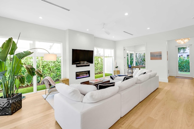 living room featuring recessed lighting, ceiling fan with notable chandelier, a fireplace, visible vents, and light wood-type flooring