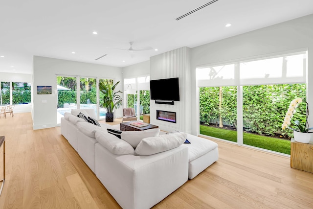 living room with light wood-style floors, a fireplace, a ceiling fan, and recessed lighting