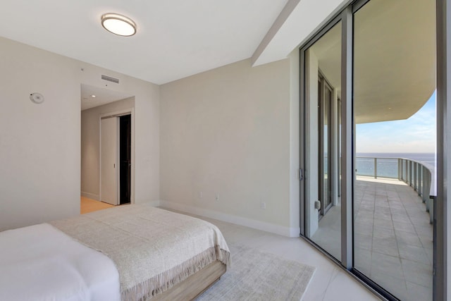 bedroom with a water view, access to exterior, and a wall of windows