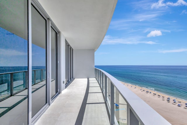 balcony with a water view and a view of the beach