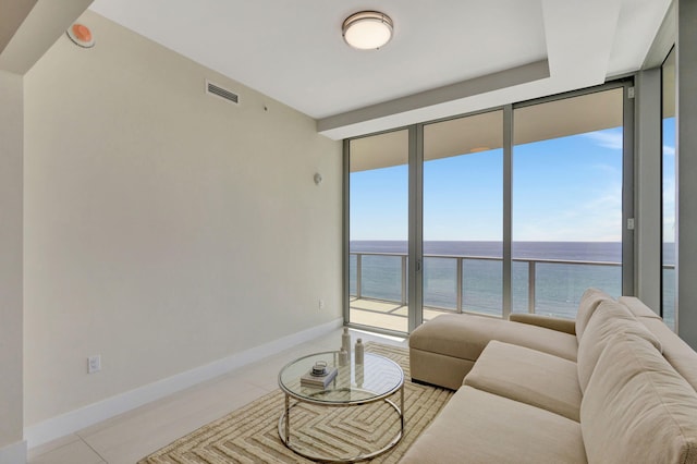 living room with expansive windows, light tile patterned flooring, and a water view