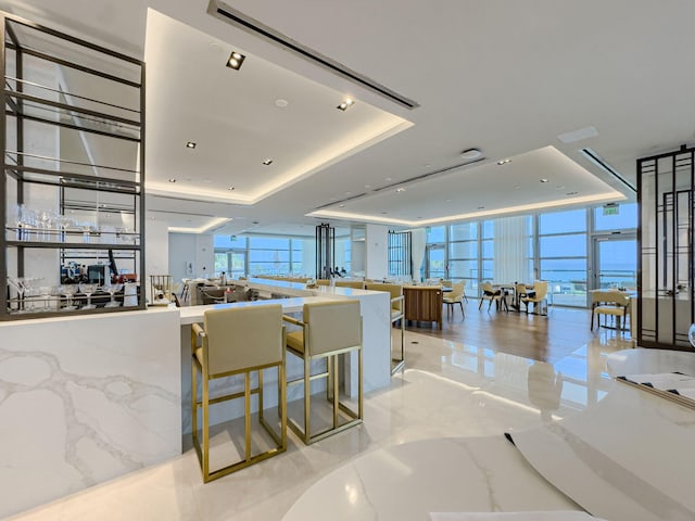 kitchen featuring a raised ceiling, expansive windows, and a kitchen bar