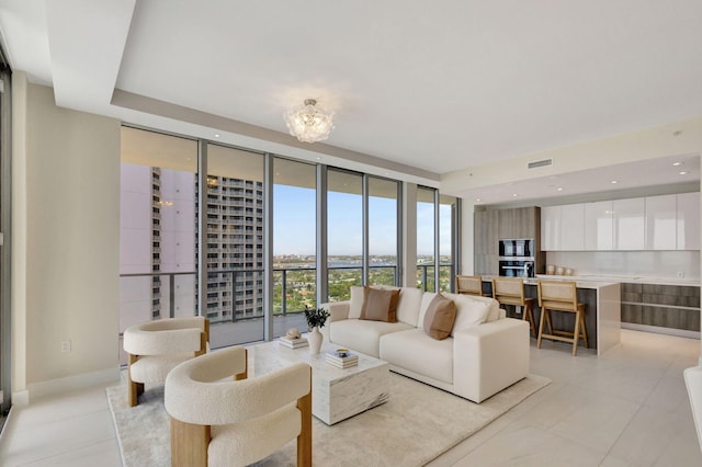 tiled living room featuring an inviting chandelier and floor to ceiling windows