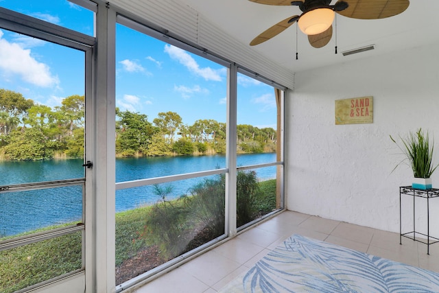 sunroom with ceiling fan and a water view