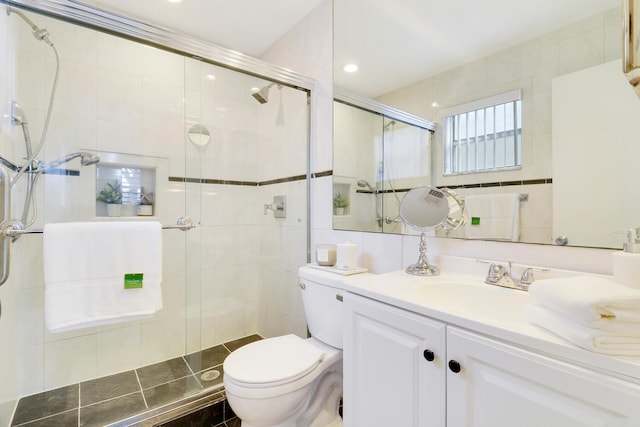 bathroom featuring vanity, a shower with shower door, toilet, and tile walls