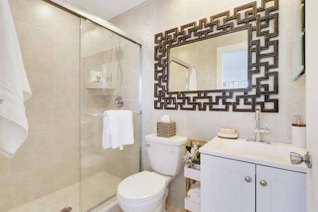 bathroom featuring vanity, a shower with door, tile walls, and toilet