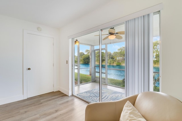 entryway with light wood-type flooring, ceiling fan, and a water view