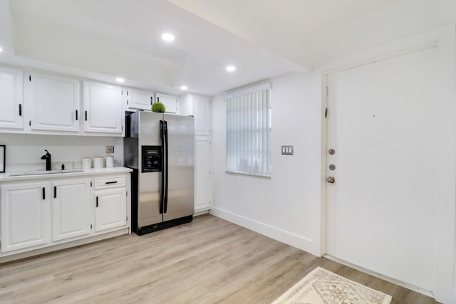 kitchen with light wood-type flooring, sink, stainless steel fridge with ice dispenser, and white cabinets