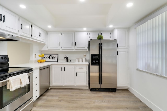 kitchen featuring sink, white cabinetry, light wood-type flooring, a tray ceiling, and stainless steel appliances