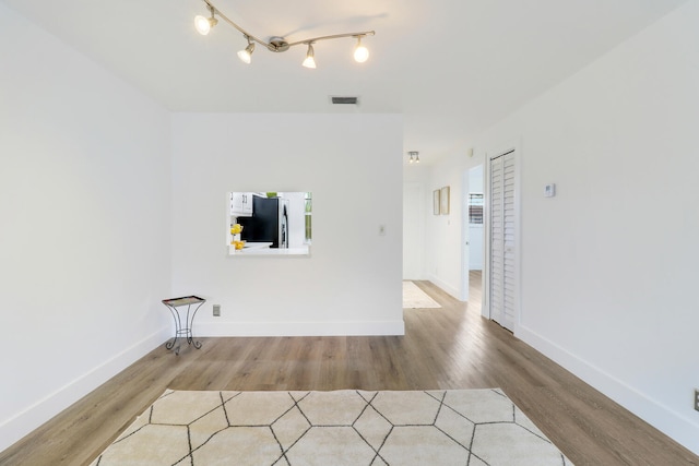 clothes washing area featuring hardwood / wood-style flooring and track lighting