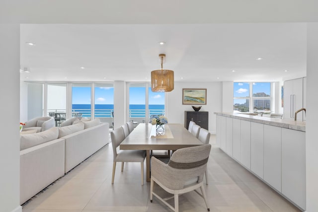 dining room with a water view, expansive windows, and light tile patterned floors