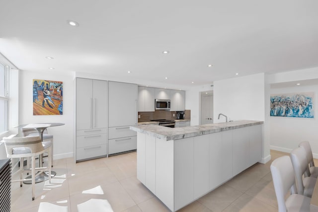 kitchen featuring white cabinetry, sink, backsplash, light tile patterned floors, and stainless steel appliances