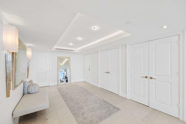 interior space featuring a tray ceiling and light tile patterned floors