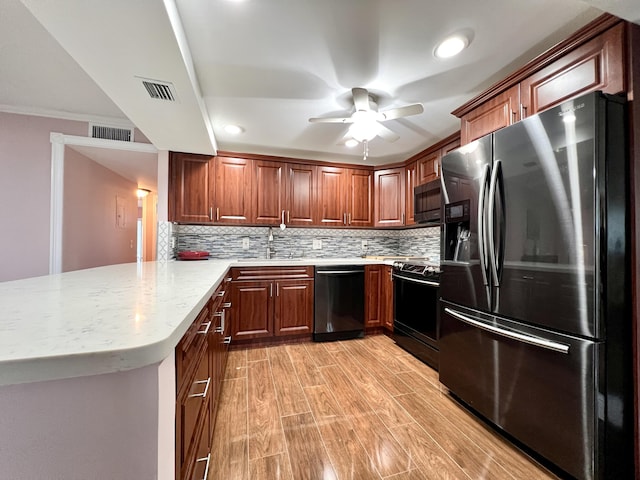 kitchen with appliances with stainless steel finishes, tasteful backsplash, sink, kitchen peninsula, and light wood-type flooring