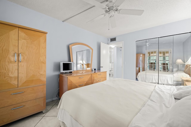 tiled bedroom with ceiling fan and a textured ceiling