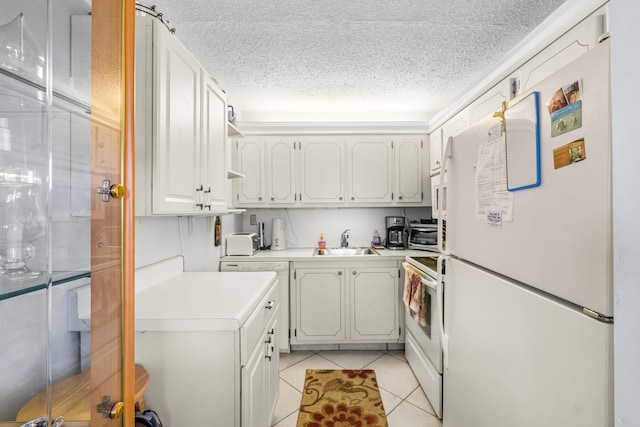 kitchen with white cabinetry, sink, light tile patterned flooring, and white appliances