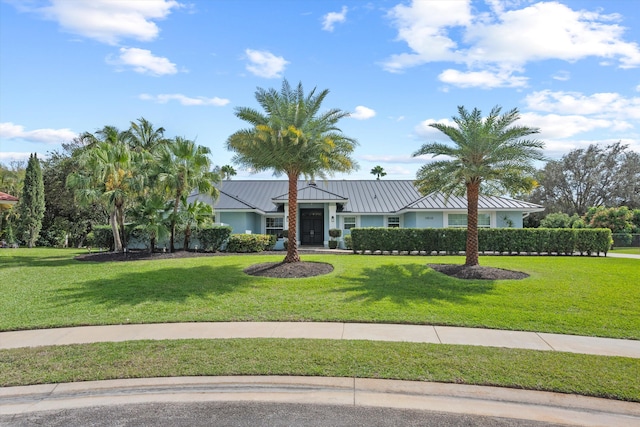 ranch-style house featuring a standing seam roof, metal roof, a front lawn, and stucco siding