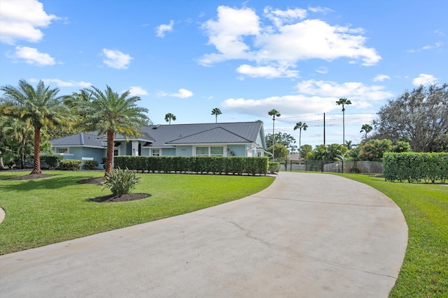 single story home featuring metal roof, driveway, a front yard, and fence