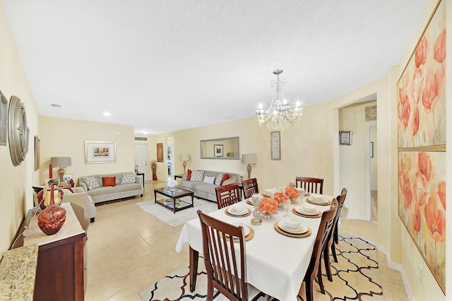 dining room featuring light tile patterned flooring, a notable chandelier, and a textured ceiling