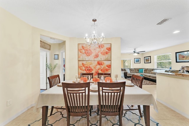 dining space featuring ceiling fan with notable chandelier, a textured ceiling, and light tile patterned floors