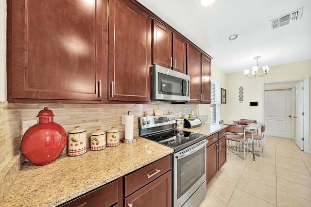 kitchen featuring light tile patterned flooring, backsplash, a notable chandelier, stainless steel appliances, and light stone countertops