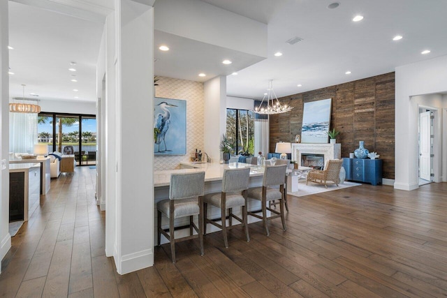 kitchen featuring dark hardwood / wood-style flooring, a fireplace, a breakfast bar, and a notable chandelier