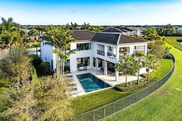 back of property with a fenced in pool, a yard, and a patio