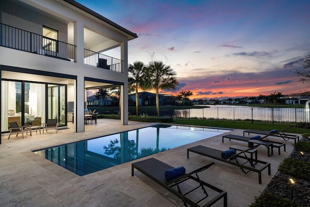 pool at dusk with a patio area