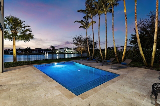 pool at dusk with a patio and a water view