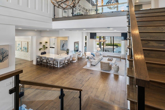 living room with hardwood / wood-style flooring, a chandelier, and a towering ceiling