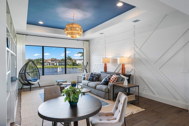 living room featuring a water view, wood-type flooring, and a tray ceiling