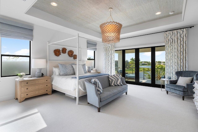 carpeted bedroom with french doors, a raised ceiling, multiple windows, and access to outside